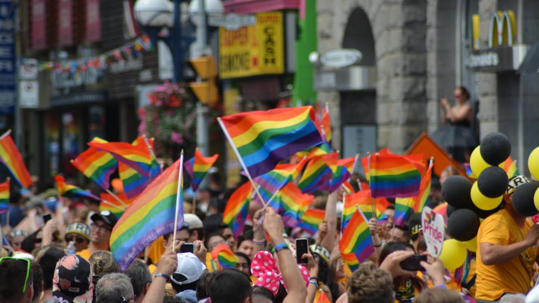 Foto van een menigte, zwaaiend met regenboogvlaggen