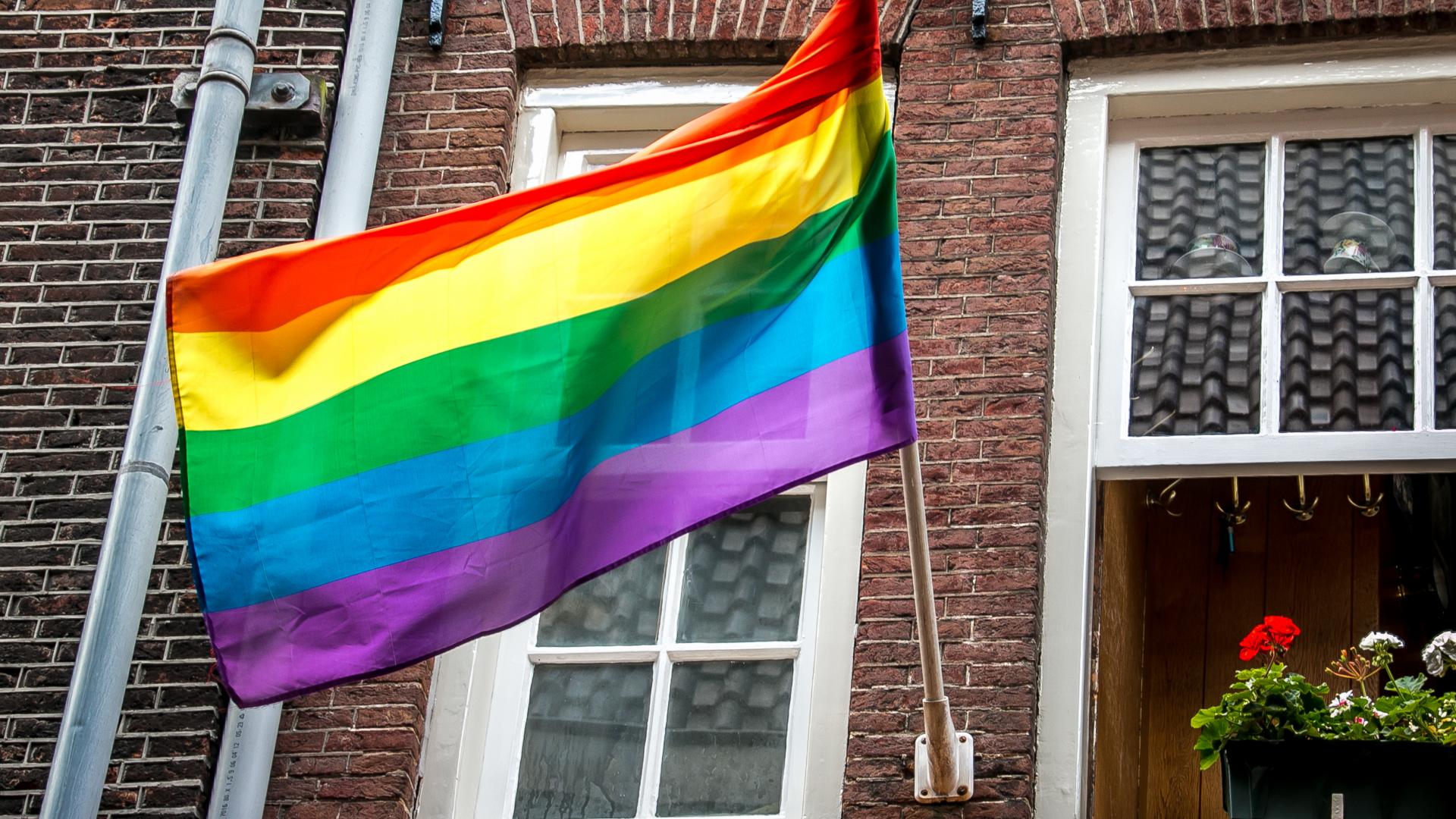 Foto van een regenboogvlag, hangend van een huis