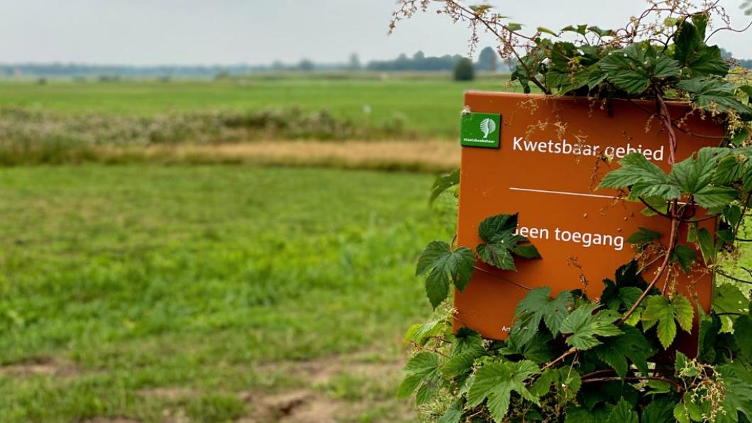 Foto van een van de weilanden aan de Oevers S, met op de voorgrond een bordje dat leest: "kwetsbaar gebied, niet betreden"